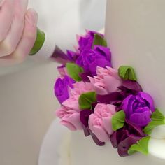 a close up of a cake with purple flowers on the front and green leaves on the side