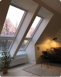 a living room with three large windows and a couch in the corner next to it