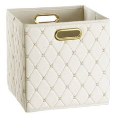 a white storage box with gold handles on the front and bottom, in quilted leather