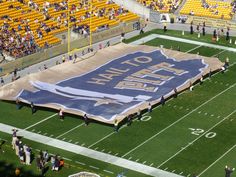 an aerial view of a football field with a banner in the middle and fans standing on the sidelines