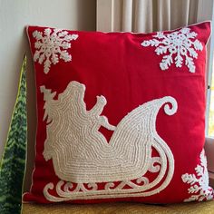 a red pillow with white snowflakes and a sleigh on the front