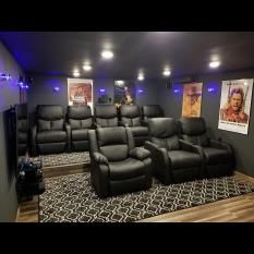 a home theater with two recliners in front of the screen and three movie screens on the wall