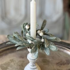 a candle that is sitting on top of a table with holly and berries around it