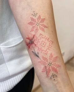 a woman's arm with a red and black flower tattoo on the left forearm