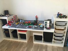 a toy table with lots of toys on it and storage bins underneath the table