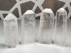 three clear crystal blocks sitting next to each other on a white counter top with geometric design behind them