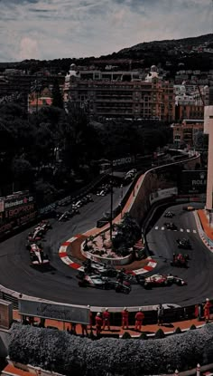 an aerial view of a race track with cars driving on it and buildings in the background