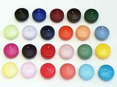 several different colored candles sitting next to each other on a white surface with one candle in the middle