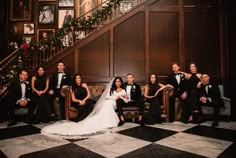 a bride and groom posing for a photo with their wedding party in front of the staircase