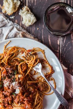 spaghetti with meat sauce and parmesan bread on a plate next to a glass of wine