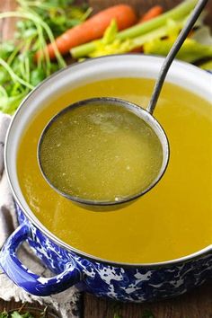 a bowl filled with soup next to carrots and celery on a table