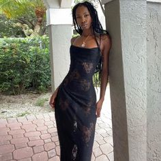 a woman in a black dress standing on a porch with her hand on her hip