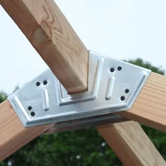 a close up of a wooden structure with metal brackets on it's sides and trees in the background