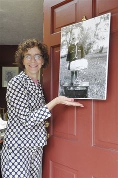 a woman standing in front of a red door holding up a sign with an image on it