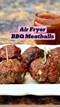 meatballs with toothpicks and garnishes on a white plate next to a jar of ketchup