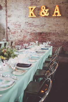 the tables are set with place settings for dinner and wine glasses on them, along with lighted letters that spell out k & a