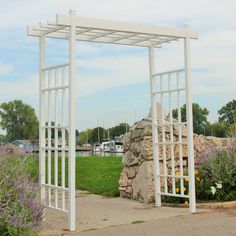 a white metal structure sitting in the middle of a park next to flowers and trees