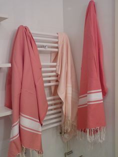 two pink towels hanging on the wall next to a radiator and towel rack