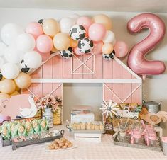 a table topped with lots of food and balloons in front of a barn shaped wall