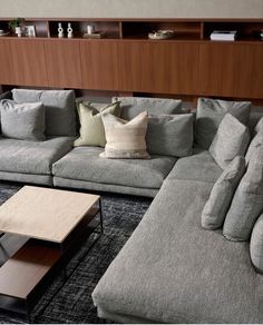 a large sectional couch with pillows on it in a living room next to a coffee table