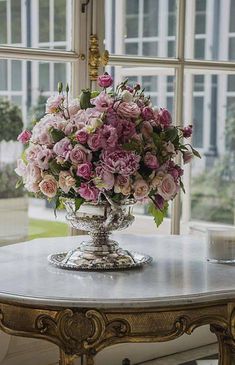 a vase filled with pink flowers sitting on top of a table next to a window