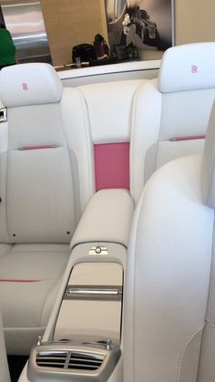 the interior of a car with white leather and pink trims, including an electronic device