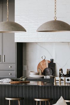 two pendant lights hanging over a kitchen island