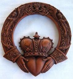 a carved wooden frame with a crown on it's head and two hands in the middle