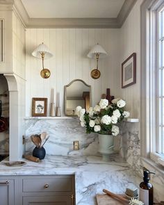 a kitchen with marble counter tops and white flowers in a vase on the counter top