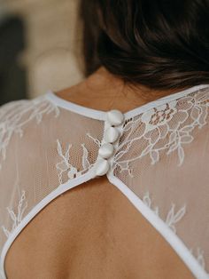 the back of a woman's bra with white lace and buttons on her chest