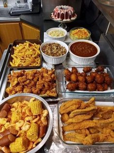 several trays filled with different types of food on top of a metal countertop