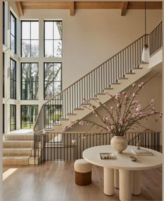 a vase with flowers sitting on top of a table in front of a stair case