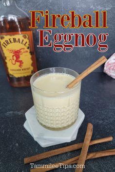 an eggnog in a glass with cinnamon sticks and a bottle of fireball eggnog next to it