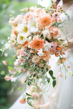 a bridal holding a bouquet of peach and white flowers