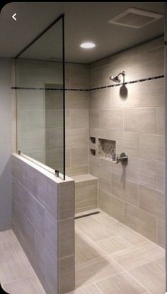 a walk in shower sitting next to a white tiled wall and floor with lights on