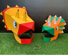 two paper mache animals sitting on top of green grass next to a black wall