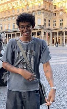 a young man with glasses holding an umbrella in front of a building and smiling at the camera