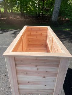 a wooden box sitting in the middle of a parking lot next to some trees and grass