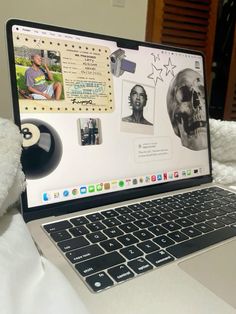 an open laptop computer sitting on top of a white bed next to a stuffed animal