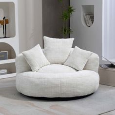 a living room with a round chair and white pillows on the floor in front of it