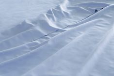 an unmade bed with white sheets and pillows