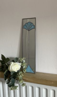 a mirror sitting on top of a radiator next to a vase with flowers