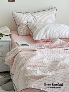 a bed with pink and white striped comforter next to a lamp on a nightstand