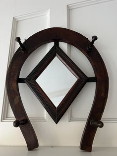 a mirror mounted to the side of a door with two hooks on each side and a diamond in the middle