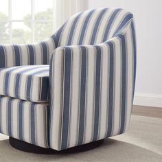 a blue and white striped chair sitting on top of a carpeted floor next to a window