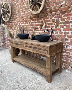 two sinks are sitting on top of a wooden table in front of a brick wall