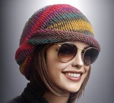 a woman wearing sunglasses and a knitted hat with stripes on the side, smiling