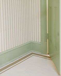 the corner of a room with green walls and striped wall paper on the floor,