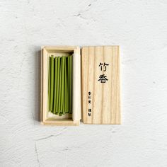 a wooden box filled with green beans and chopsticks next to a white wall