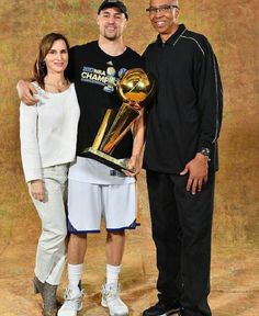 two men and a woman posing with a basketball trophy